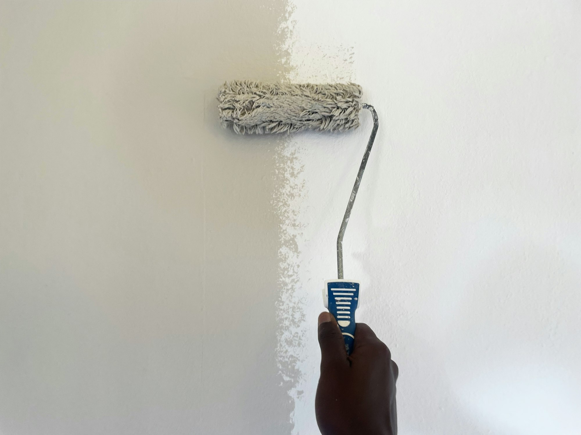 Pintor aplicando tinta com rolo em parede interna — Unsplash